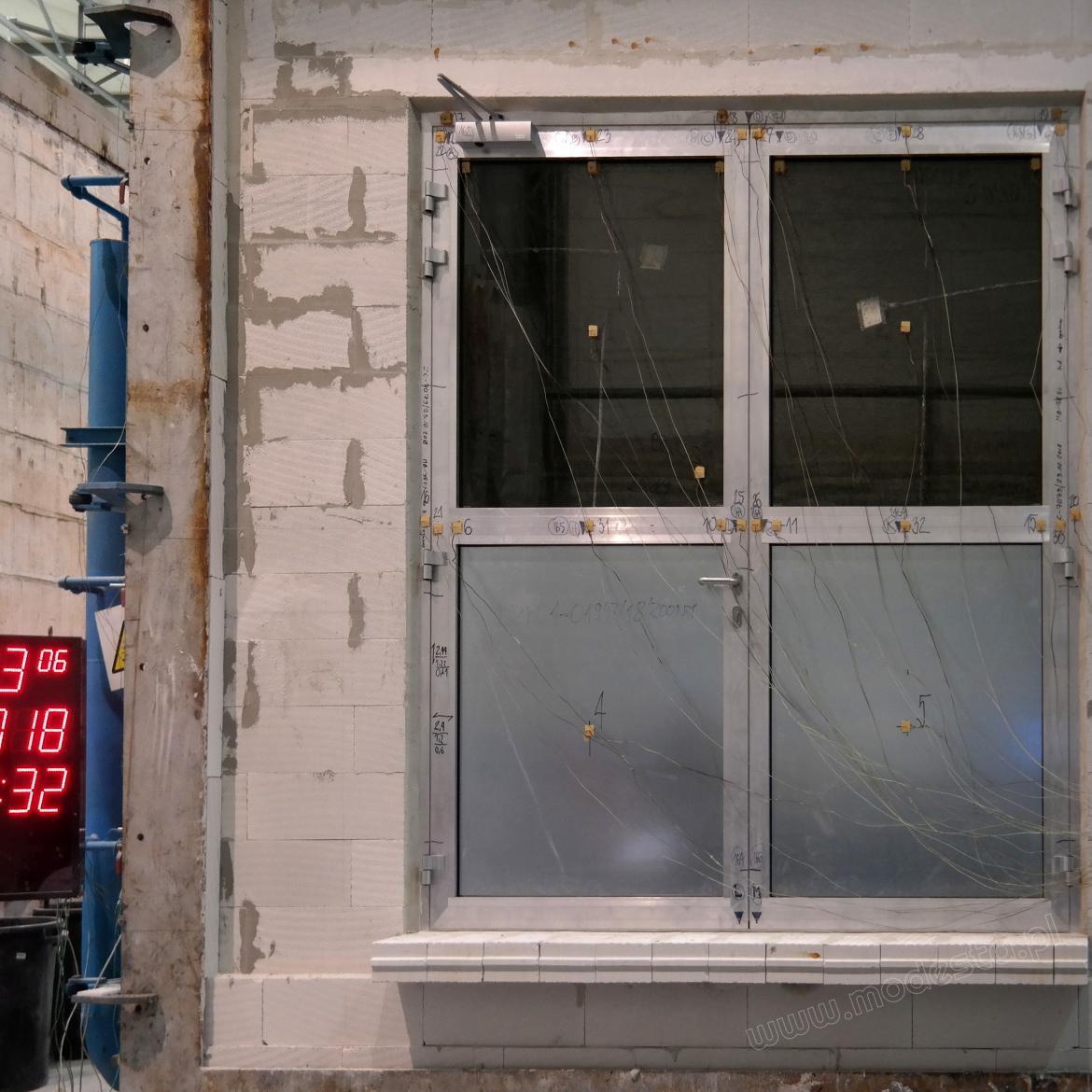 Drzwi aluminiowe ppoż. z termoelementami podczas badań ogniowych w laboratorium.